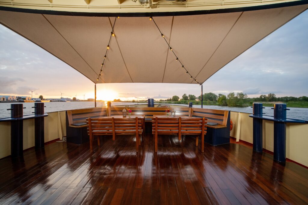 wooden chairs and the tables with flowers and lanterns on top in the boat